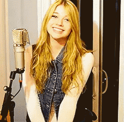 a woman with long blonde hair is smiling in front of a microphone