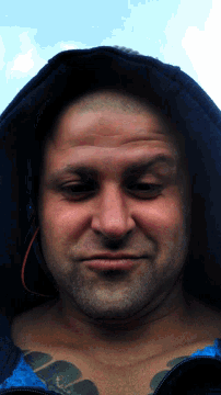 a man with a tattoo on his chest is wearing a hooded jacket