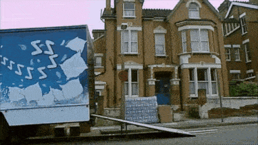 a moving truck is parked in front of a large brown house
