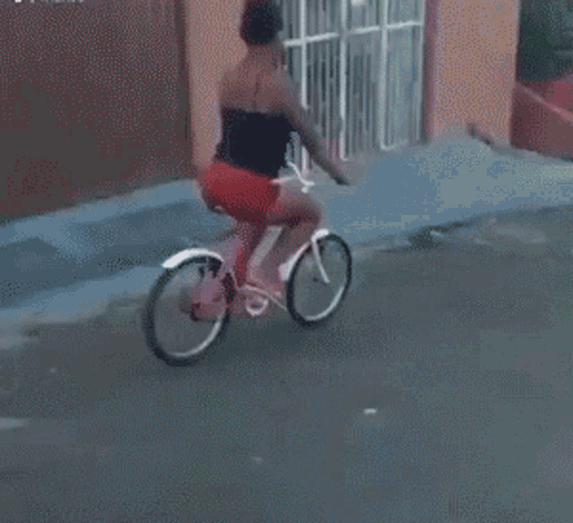 a woman is riding a bike down a street in front of a building with a sign that says mcell
