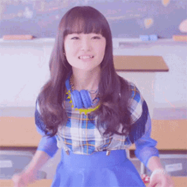 a girl wearing headphones and a plaid shirt smiles