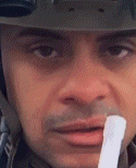 a close up of a man wearing a helmet and holding a stick in his mouth .