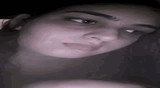a close up of a woman 's face with a nose ring and earrings .