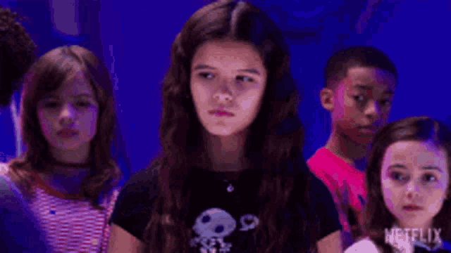 a group of young girls are standing in a dark room with netflix written on the bottom of the screen .
