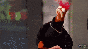 a muppet wearing a black turtleneck and a necklace with abc news written on the bottom right
