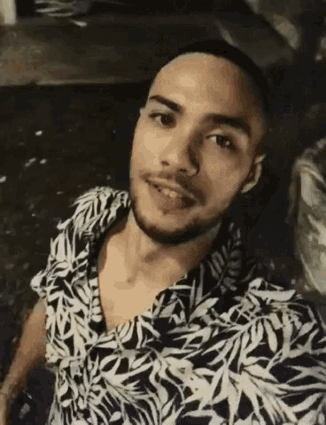 a man with a beard is taking a selfie while wearing a floral shirt .