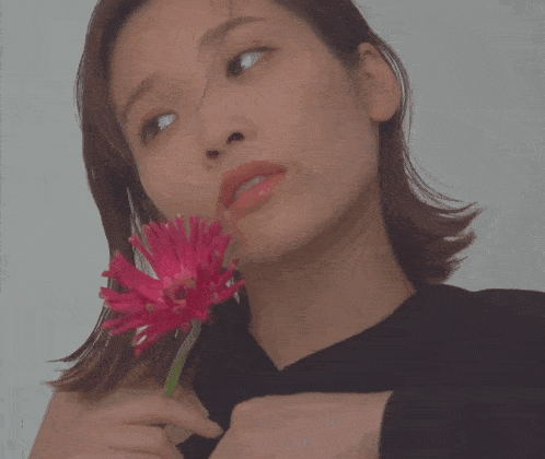 a woman holds a pink flower in her hand