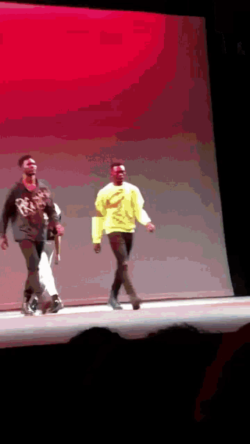 a man in a yellow sweater is walking on stage