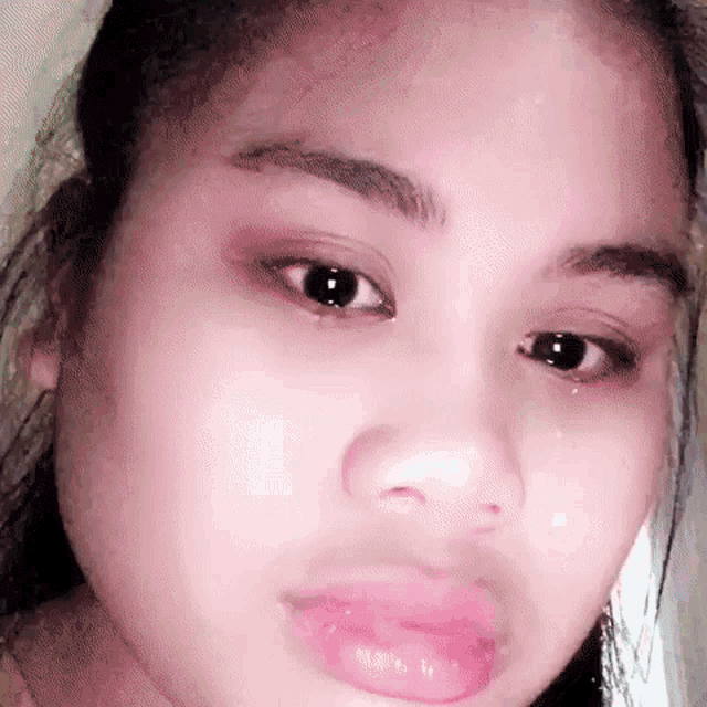 a close up of a woman 's face with a tear running down her face .