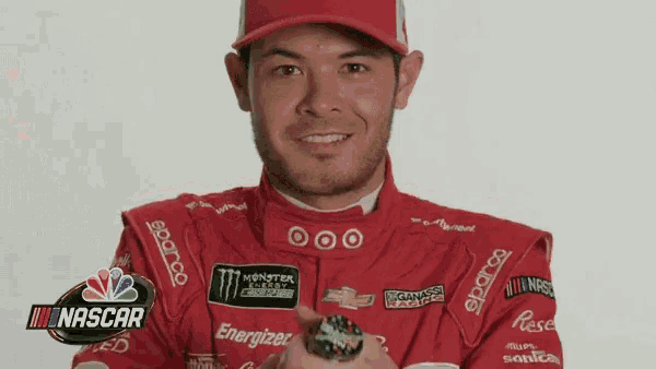 a man wearing a red racing suit and a red hat is holding a ring .
