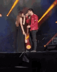 a man and a woman are singing on a stage