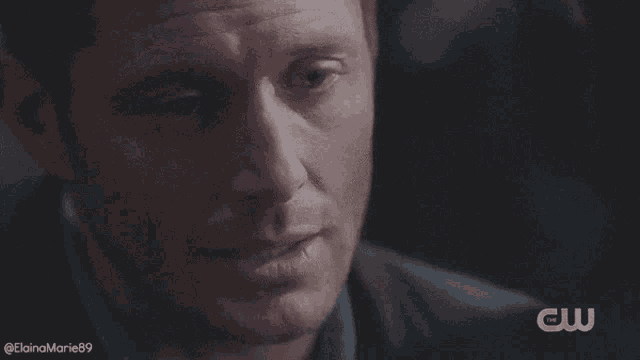 a close up of a man 's face with a cw logo on the bottom right