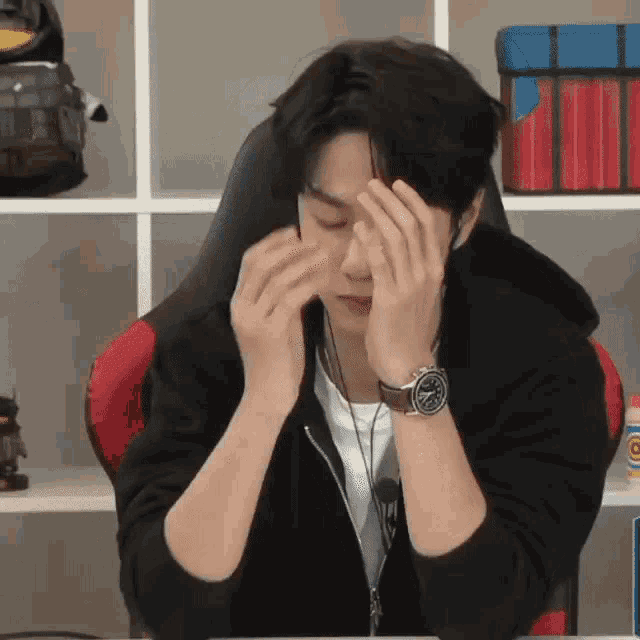 a man with a watch on his wrist is covering his face