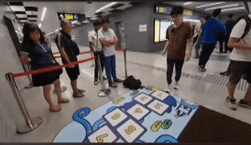 a group of people are standing around a hopscotch board