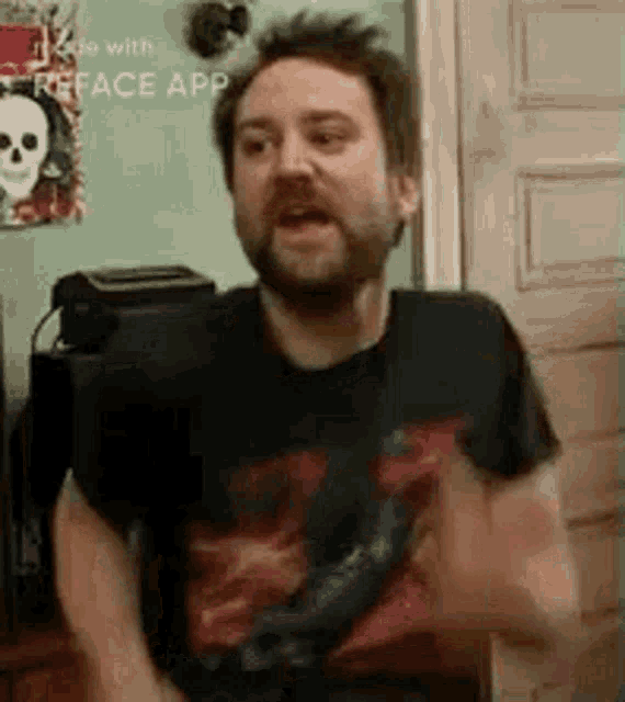 a man with a beard is standing in front of a door with his arms outstretched .