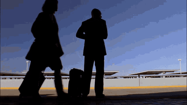 a man and a woman are walking down a street with a suitcase