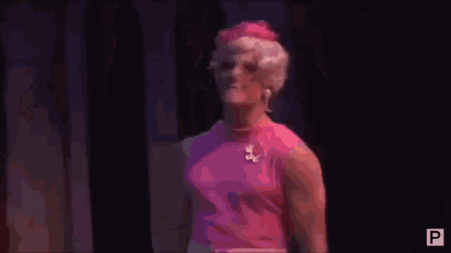 a group of people standing on a stage with a woman in a pink dress .