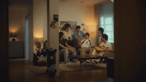 a group of young people are sitting in a living room with their arms up