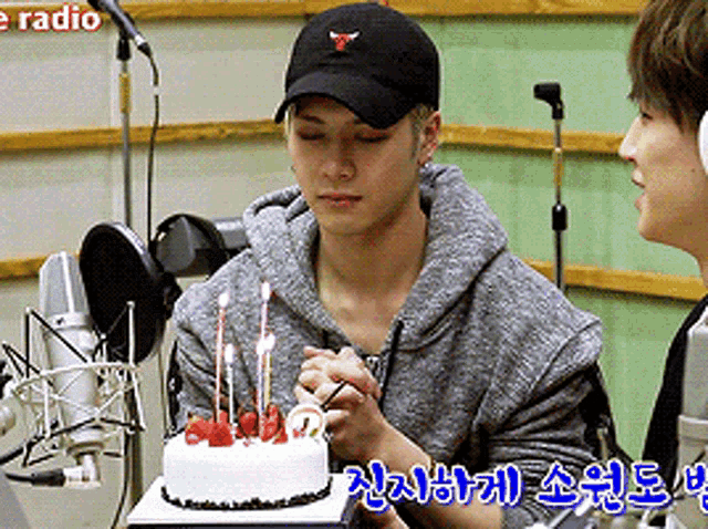a man wearing a black hat is holding a cake with candles