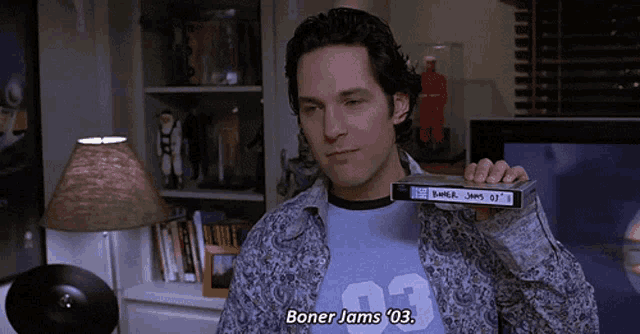 a man in a blue shirt with the number 03 on it is holding a tape that says boner jams 03
