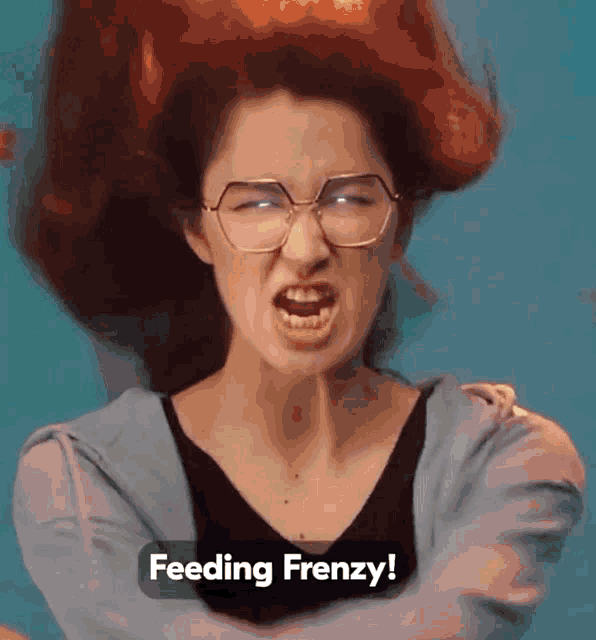 a woman with red hair and glasses is making a funny face and the caption says feeding frenzy