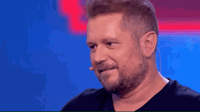 a man with a beard and a microphone in his ear is smiling