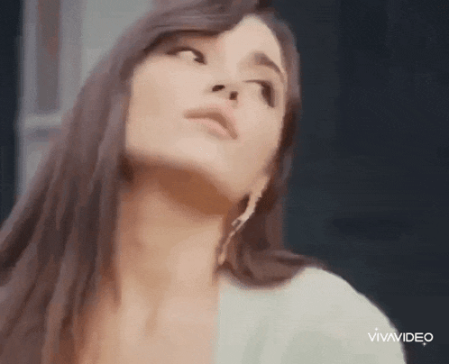 a close up of a woman 's face with long hair and earrings .