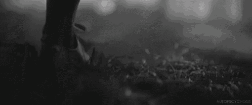 a black and white photo of a person standing in the grass with a gun .