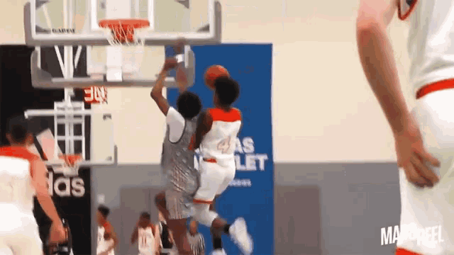 a basketball game is being played in front of a wall that says adidas
