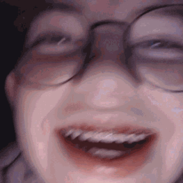 a close up of a person wearing glasses making a funny face
