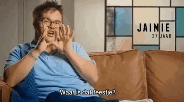 a man sitting on a couch with the name jaimie 27 jaar written on the wall behind him