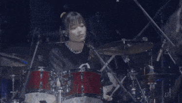a woman is playing drums on a stage with a microphone