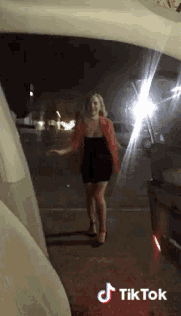 a woman in a black dress is standing in a parking lot with a tiktok watermark