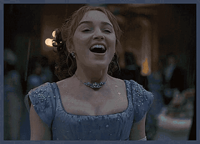 a woman wearing a blue dress and a necklace is smiling with her eyes closed