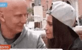 a man and a woman are kissing and the woman is wearing a white hat .