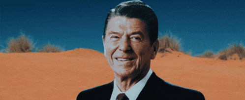 a man in a suit and tie is smiling in front of a desert landscape