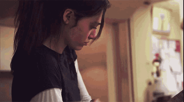 a woman in a black shirt is standing in front of a fridge
