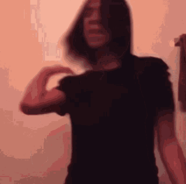 a woman in a black shirt is standing in front of an orange wall .