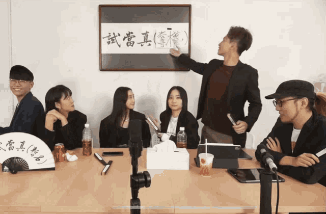 a group of people sitting around a table with a fan in front of them
