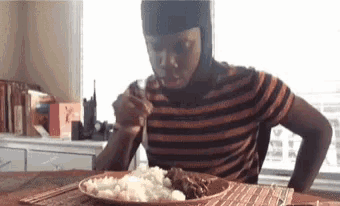 a man wearing a helmet is eating a plate of food with a fork