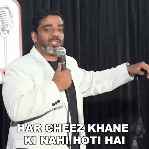a man in a white jacket is holding a microphone and says har cheez khane ki nahi hoti hai
