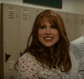 a woman with red hair is smiling in front of lockers with the letter o on them