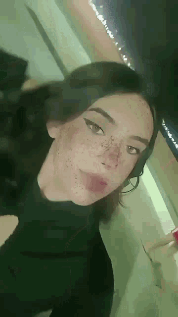 a girl with freckles on her face is wearing a black turtleneck sweater .