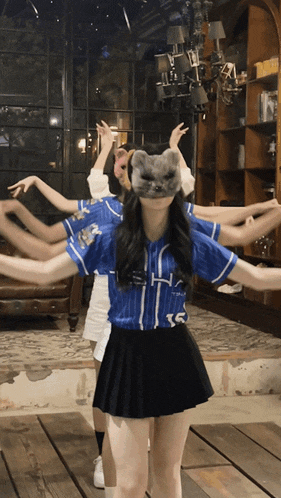 a girl wearing a cat mask is surrounded by other girls wearing baseball uniforms