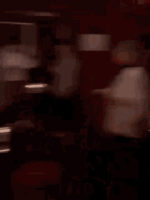 a man in a black shirt is holding a glass of wine and dancing in a club .