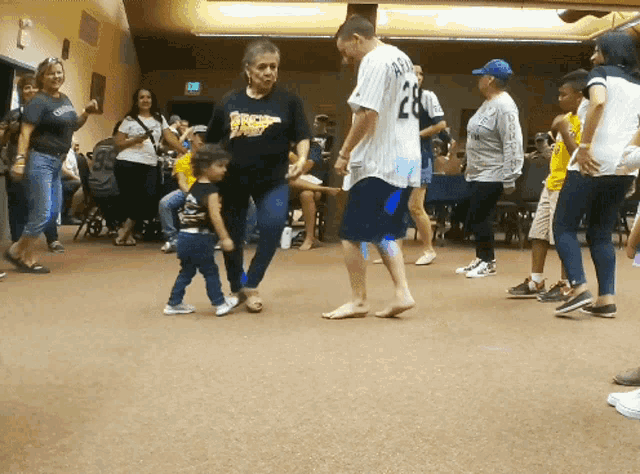 a group of people are dancing in a room with a man wearing a number 28 jersey