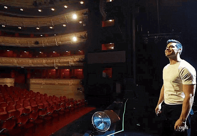 a man in a white shirt is standing in front of an empty auditorium
