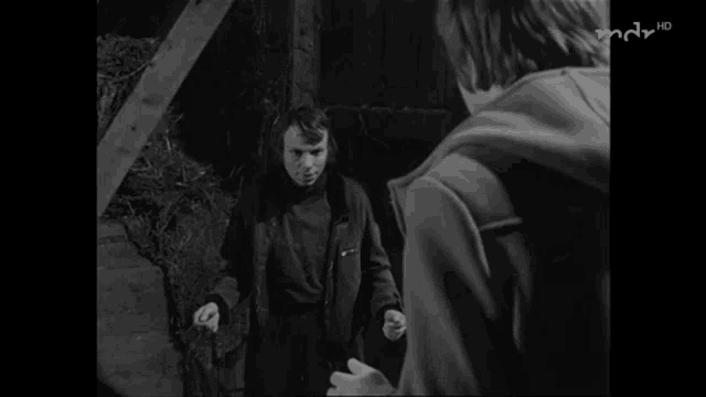 a black and white photo of a man standing next to another man with the word hd on the bottom left