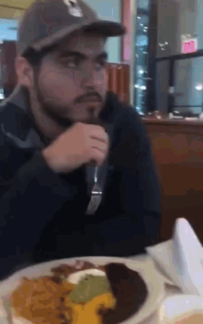 a man sitting at a table with a plate of food and a fork