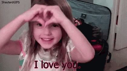 a little girl is making a heart shape with her hands while saying i love you .